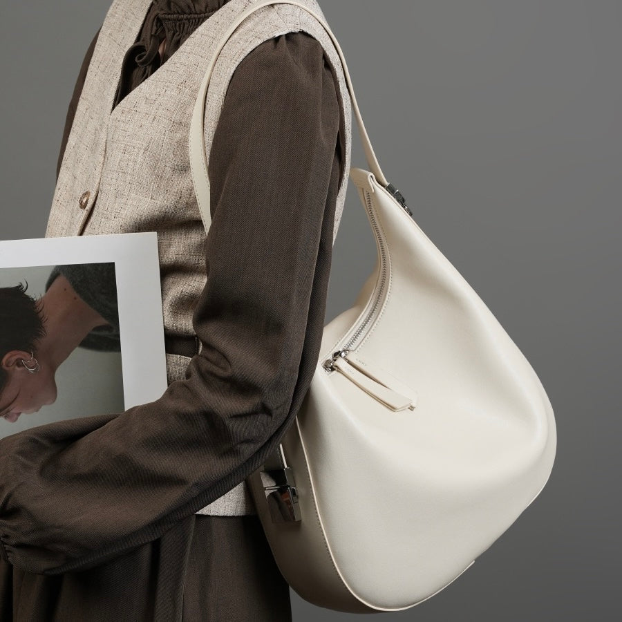 Minimalistisk designad äkta läderväska med halvmåneformad axelrem