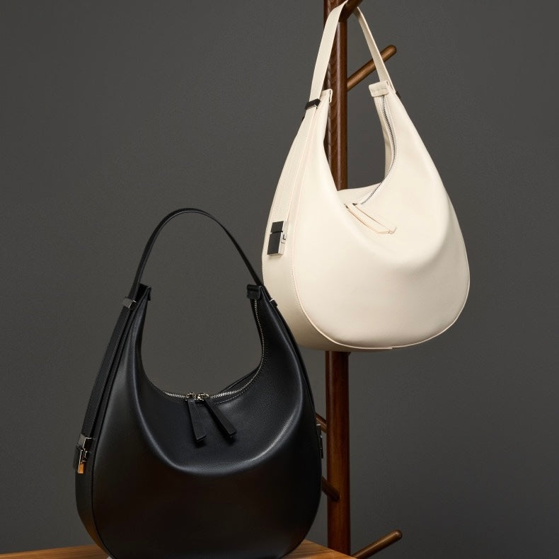 Minimalistisk designad äkta läderväska med halvmåneformad axelrem